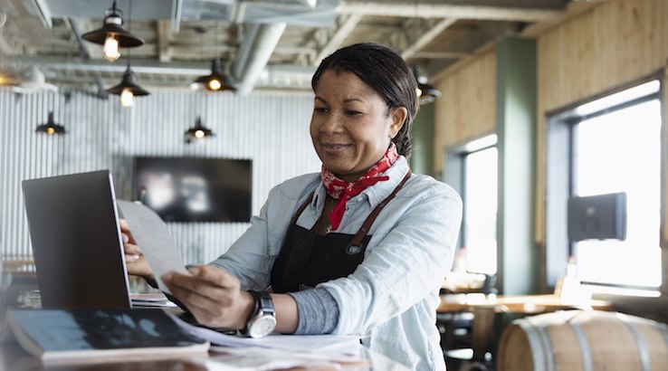 Female small business owner paying bills on computer. 